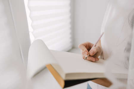 Woman draws in a sketchbook at home near the window, creativity. Drawing training.の写真素材