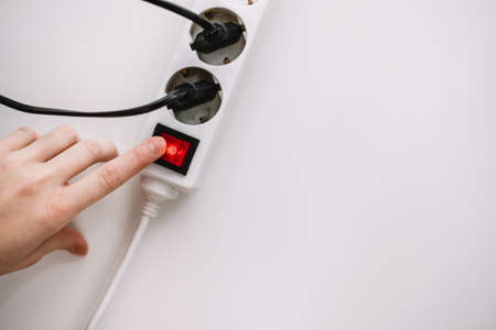 A woman turns on an electric surge protector. Protection of household appliances from electrical interference.の写真素材