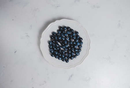 Fresh juicy blueberries in a white plate with on a white background. Close up.の写真素材