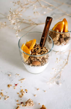 Natural yogurt and granola with slices of fruits and nuts in a glass cup, healthy breakfastの写真素材