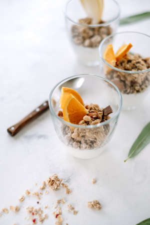 Natural yogurt and granola with slices of fruits and nuts in a glass cup, healthy breakfastの写真素材