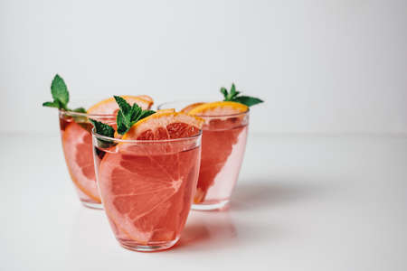Pink drink, cocktail with grapefruit slice and fresh mint on a white background. High quality photoの写真素材