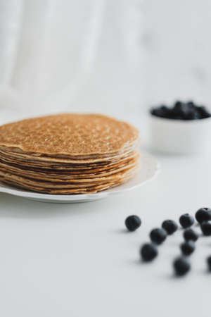 Homemade pancakes with fresh blueberries in a white plate on a white background. High quality photo