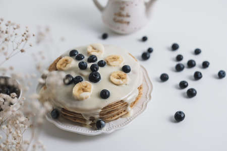 Pancakes with condensed milk with fresh blueberries and banana in a white plate on a white background. High quality photoの写真素材
