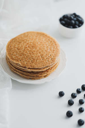 Homemade pancakes with fresh blueberries in a white plate on a white background. High quality photoの写真素材