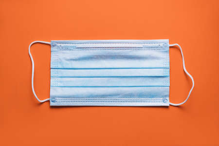 Medical protective mask isolated on orange background. Medical mask protection against pollution, virus, flu, coughing and coronavirus. High quality photoの写真素材