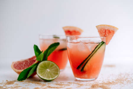 Grapefruit cocktail, lemonade with lime, mint and pieces of ice on a white table with cane sugar. High quality photoの写真素材