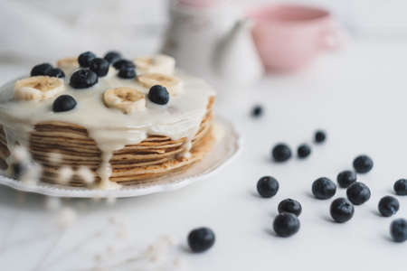 Pancakes with condensed milk with fresh blueberries and banana in a white plate on a white background. High quality photoの写真素材