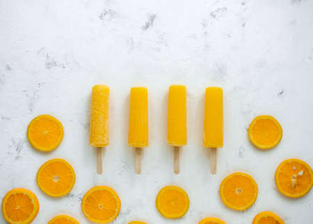 Orange fruit ice sorbet with slices of fresh orange on a white background. Stick ice cream. High quality photoの写真素材