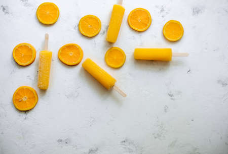 Orange fruit ice sorbet with slices of fresh orange on a white background. Stick ice cream. High quality photoの写真素材