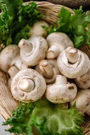 Champignon mushrooms in a basket with herbs on the table. Top view. High quality photoの写真素材