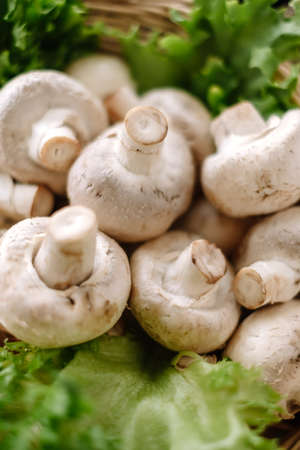 Champignon mushrooms in a wooden board with herbs on the table, close-up. High quality photoの写真素材