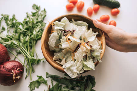 Woman cooking healthy salad with vegetables in wooden bowl. Healthy food. High quality photoの写真素材