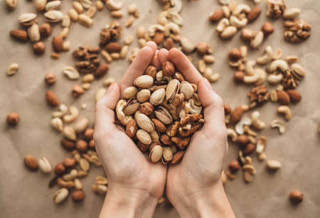 Different types of nuts, nut mix of almonds, hazelnuts, cashews, peanuts in hands. ... High quality photoの写真素材