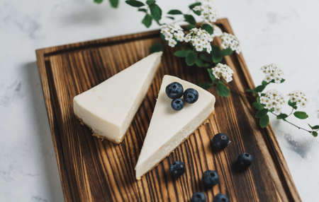 Blueberry and strawberry cheesecake on a wooden board and branch with white flowers. ... High quality photoの写真素材