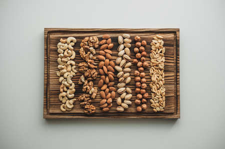 Different types of nuts, nut mix of almonds, hazelnuts, cashews, peanuts on a wooden board. High quality photoの写真素材