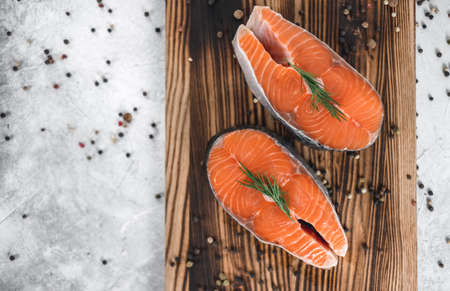 Fresh steaks of red salmon fish with spices and herbs on a wooden board. High quality photoの写真素材