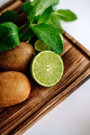 Tropical fruit, lime, kiwi and mint on a wooden board, close-up. High quality photoの写真素材
