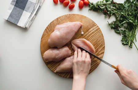 Chicken fillet on a wooden board with herbs, white background. Cooking preparation. Flat lay. High quality photoの写真素材