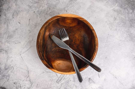 Empty wooden bowl plate with cutlery on a gray background. High quality photoの写真素材