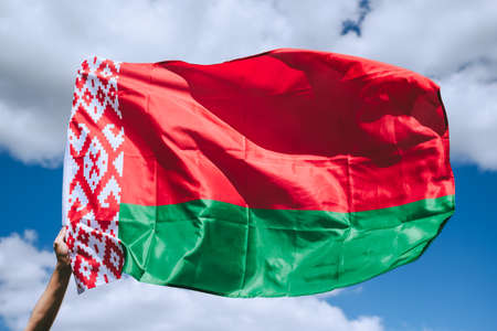 Belarus flag in hand on blue sky background. High quality photo