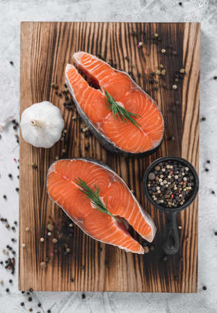 Fresh steaks of red salmon fish with spices and herbs on a wooden board. High quality photoの写真素材