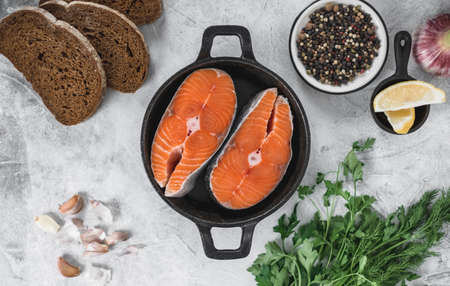 Fresh steaks of red salmon fish with spices, herbs and lemon in a black pan. High quality photoの写真素材
