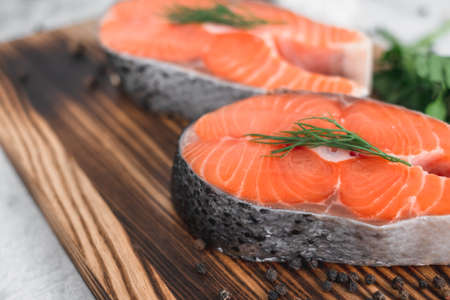 Fresh steaks of red salmon fish with spices and herbs on a wooden board. High quality photoの写真素材