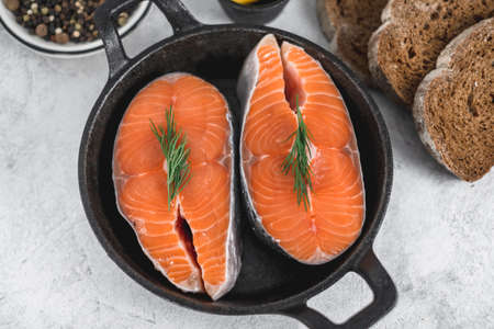 Fresh steaks of red salmon fish with spices, herbs and lemon in a black pan. High quality photoの写真素材
