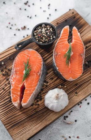 Fresh steaks of red salmon fish with spices and herbs on a wooden board. High quality photoの写真素材