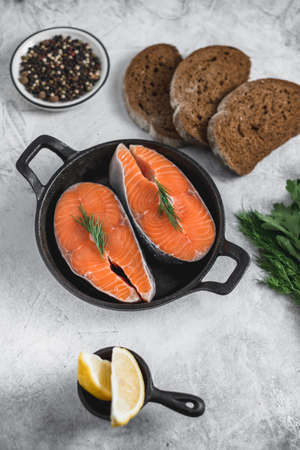 Fresh steaks of red salmon fish with spices, herbs and lemon in a black pan. High quality photoの写真素材