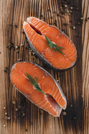 Fresh steaks of red salmon fish with spices and herbs on a wooden board. High quality photoの写真素材
