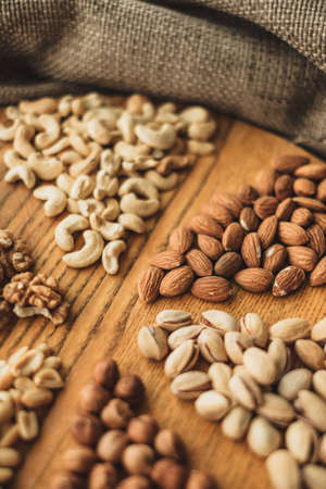 Different types of nuts, nut mix of almonds, hazelnuts, cashews, peanuts on a wooden board close-up. High quality photoの写真素材