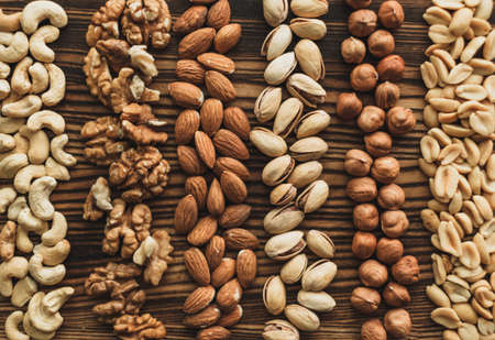 Different types of nuts, nut mix of almonds, hazelnuts, cashews, peanuts on a wooden board. High quality photoの写真素材