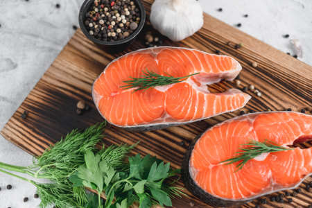 Fresh steaks of red salmon fish with spices and herbs on a wooden board. High quality photoの写真素材