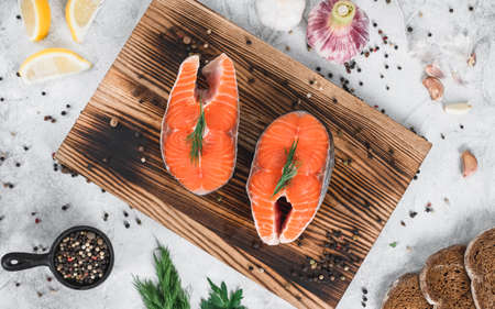 Fresh steaks of red salmon fish with spices and herbs on a wooden board. High quality photoの写真素材