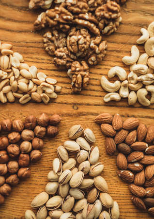 Different types of nuts, nut mix of almonds, hazelnuts, cashews, peanuts on a wooden board close-up. High quality photoの写真素材