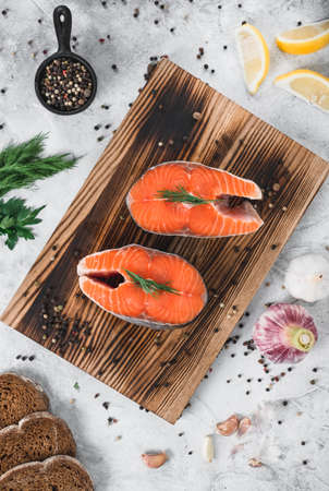 Fresh steaks of red salmon fish with spices and herbs on a wooden board. High quality photoの写真素材