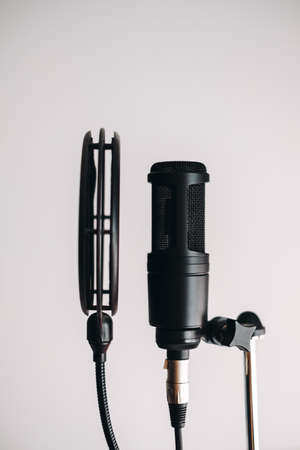 Black condenser microphone on stand with pop filter isolated on gray background. High quality photoの写真素材