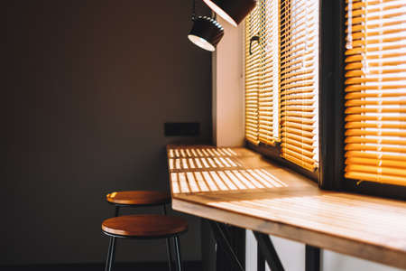 Modern wooden table on the kitchen near big window with curtain. Warm light. Interior detail. High...