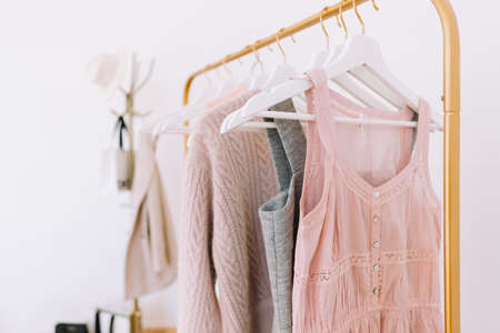 Gold floor wardrobe rack with pastel color fashion clothes near white wall. Shopping concept. High...