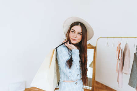 Stylish caucasian young woman in hat and business suit with shopping bag in fashion boutique while shopping. High quality photoの写真素材