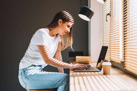 Young caucasian woman using laptop computer at modern home. Home leisure. High quality photoの写真素材
