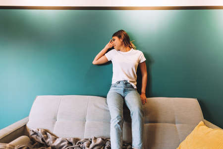Cheerful young woman funny posing while sitting on a sofa in modern living room. High quality photoの写真素材
