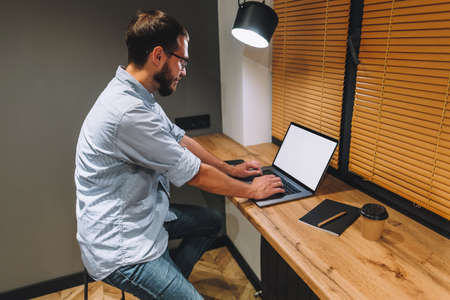 Young caucasian bearded man work at home, freelance work, use laptop computer. High quality photoの写真素材