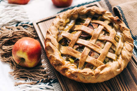 Homemade apple pie on a wooden board with cinnamon and a golden crust. Autumn season. High quality photoの写真素材