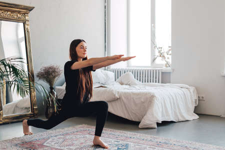 Beautiful brunette fitness woman make stretching exercises, doing yoga indoors at home. Staying fit and healthy. High quality photoの写真素材