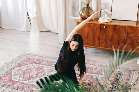 Beautiful brunette fitness woman make stretching exercises, doing yoga indoors at home. Staying fit...