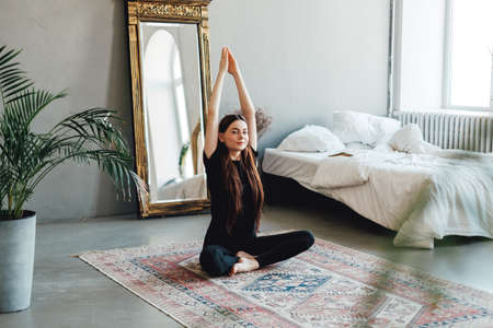 Beautiful brunette fitness woman meditate, doing yoga indoors at home. Staying fit and healthy. High...