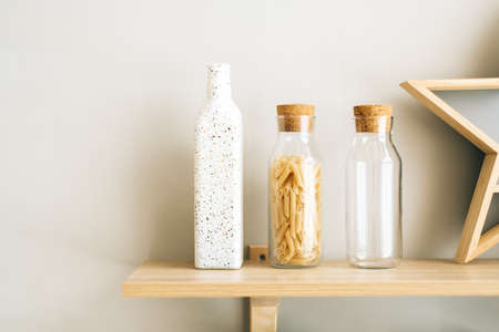 Wheat Italian pasta in glass jar on a wooden shelf in the kitchen. High quality photo